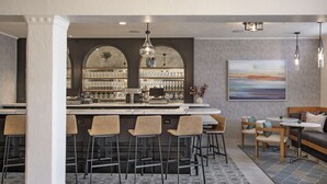 A modern bar area with a high bar counter, multiple stools, and a large wine rack.