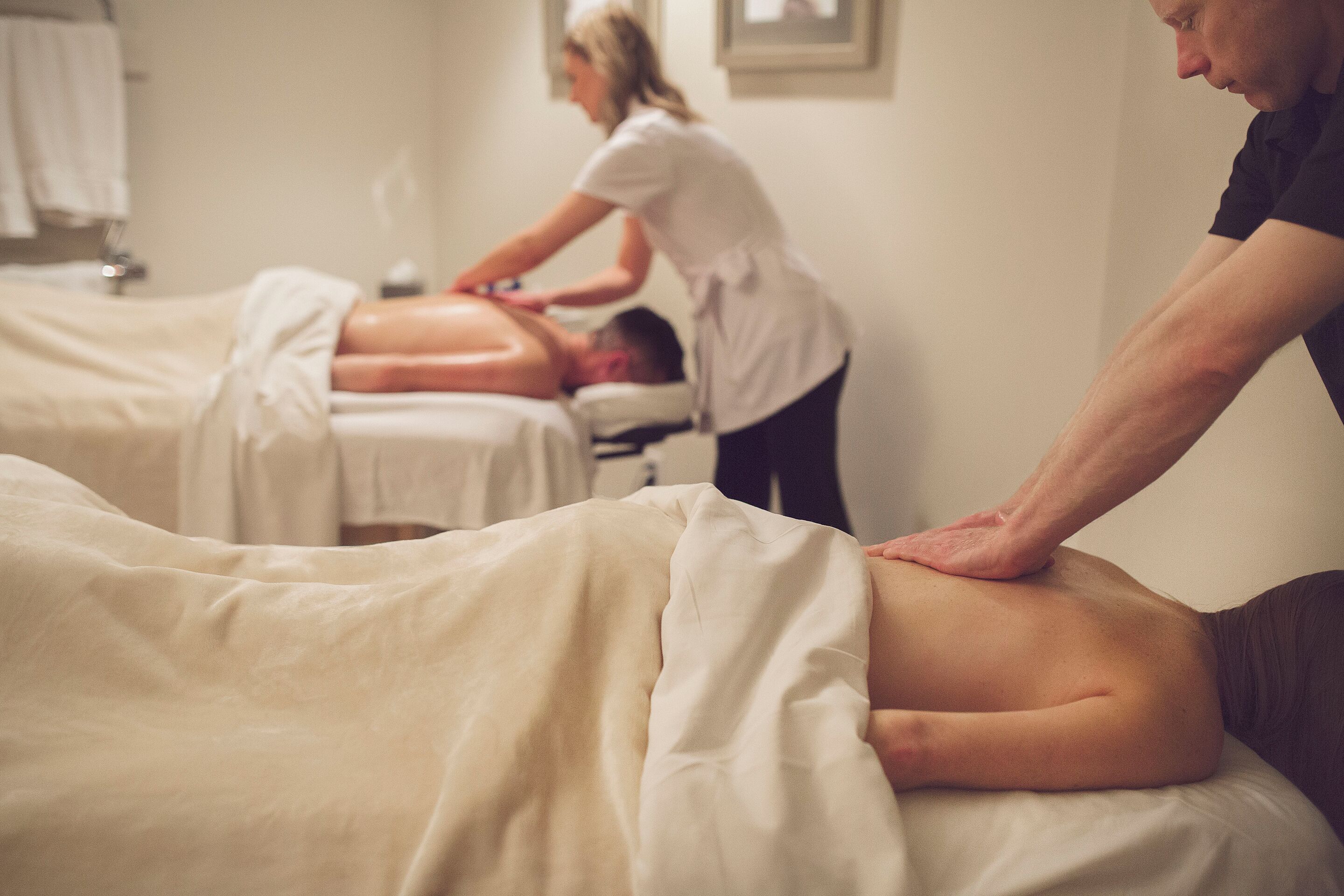 Een massageruimte met twee cliënten die een rugmassage krijgen.