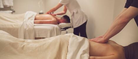 Een massageruimte met twee cliënten die een rugmassage krijgen.
