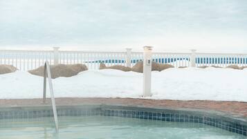 A swimming pool with a white fence and rocks in the background.