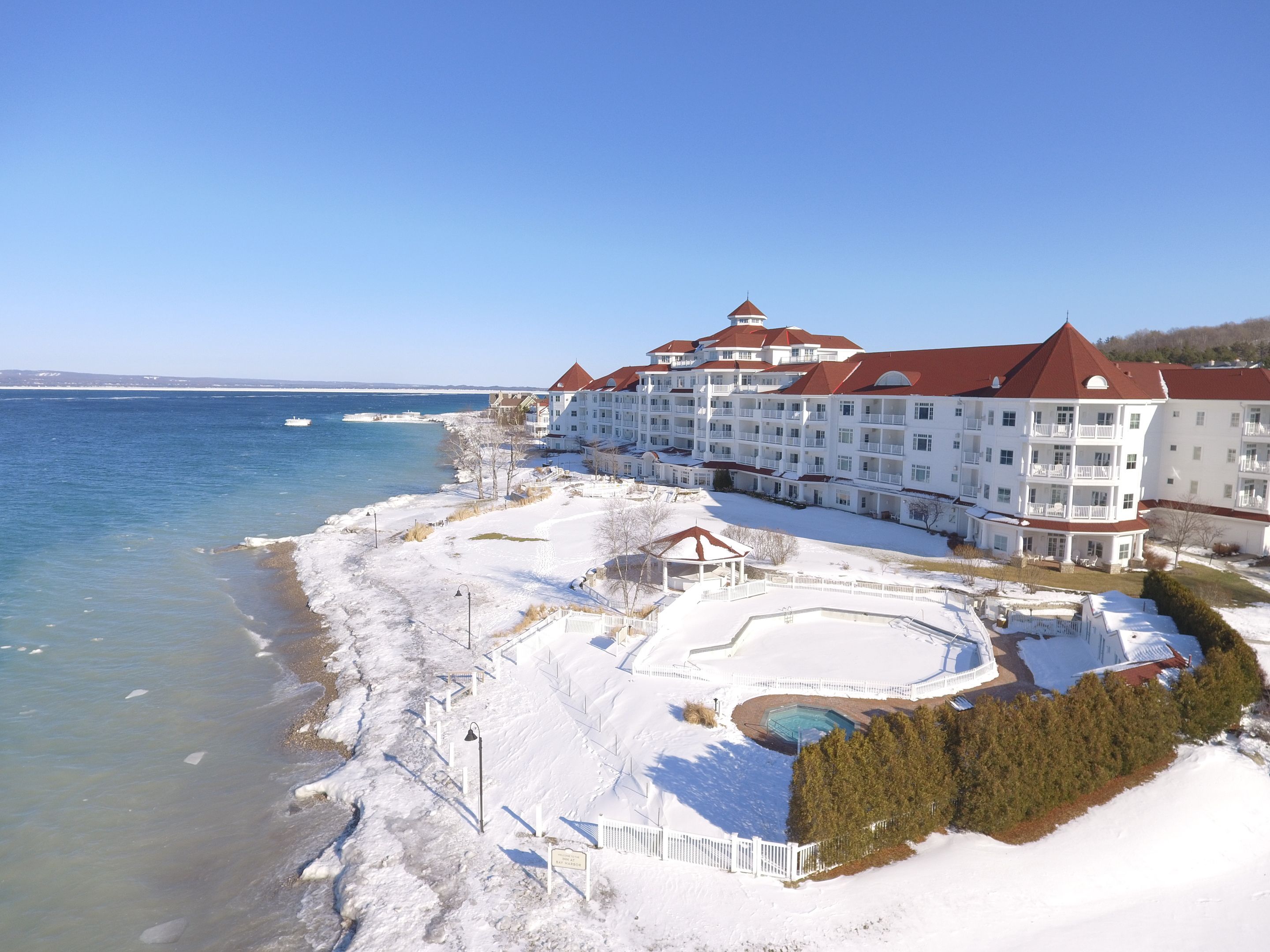 A large hotel with multiple balconies overlooking a snowy beach and a clear blue sky.