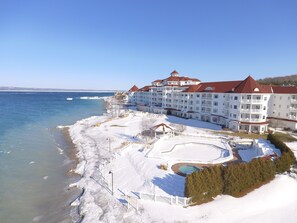 A large hotel with multiple balconies overlooking a snowy beach and a clear blue sky.
