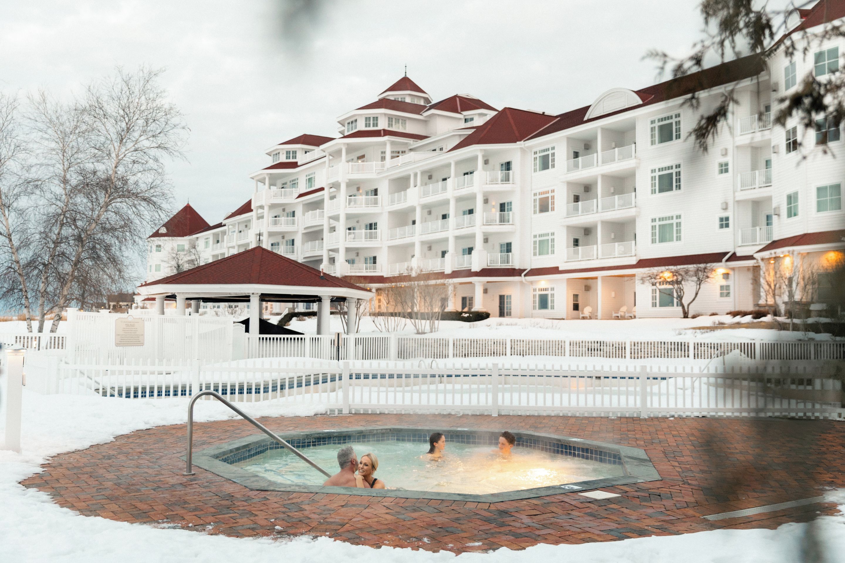 A hotel with multiple balconies, a swimming pool, and a covered area.