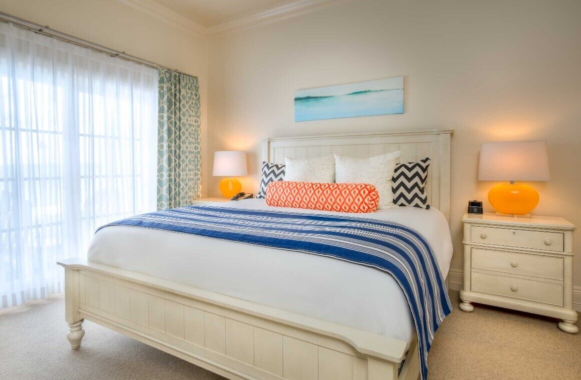 A neatly arranged bedroom with a bed, two bedside tables, and a window with curtains.