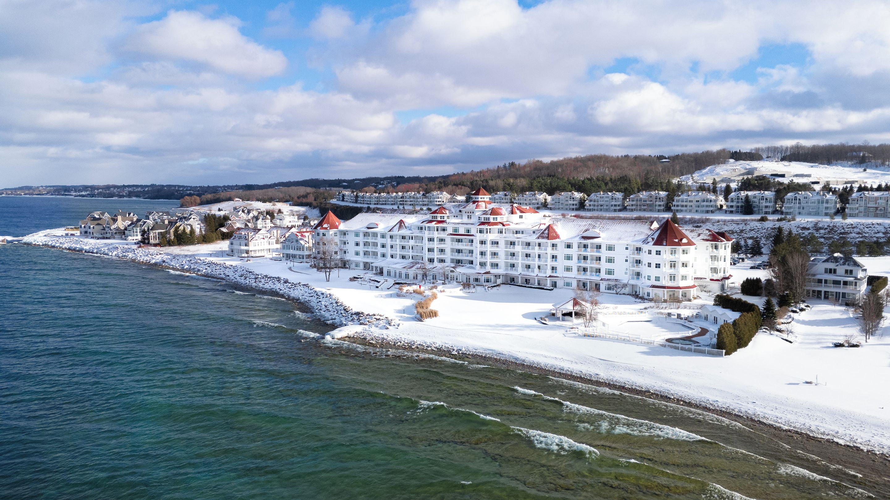 A coastal hotel with multiple buildings, a snow-covered beach, and a view of the sea.