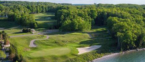 A golf course with a water body adjacent to it.