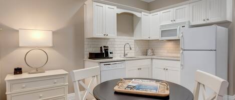 A modern kitchen with white cabinetry, a round dining table, and a magazine on the table.