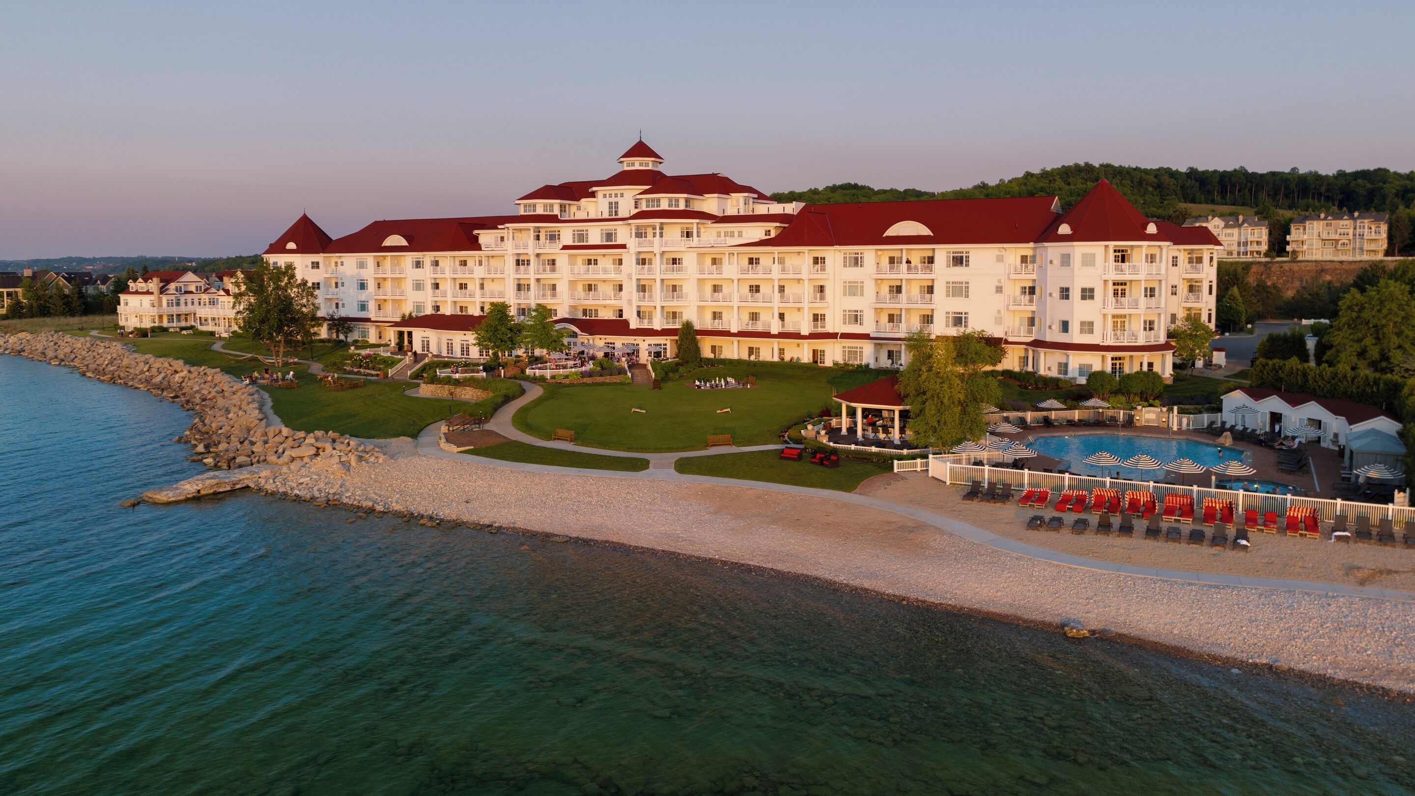 Ein großes Hotel mit mehreren Balkonen, einem Swimmingpool und einem Strandbereich.