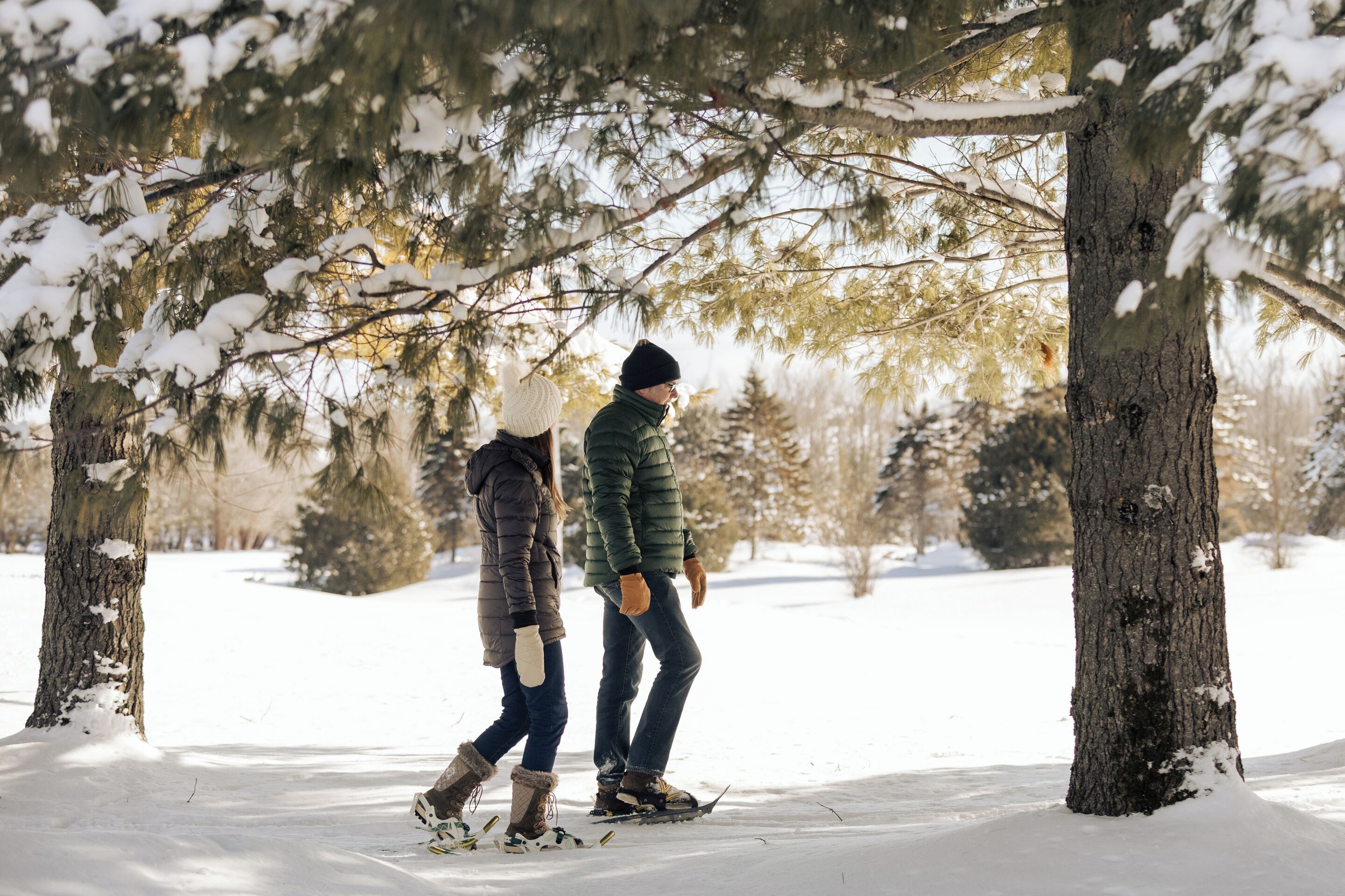 Une scène hivernale en plein air, avec deux personnes qui marchent en portant des raquettes.