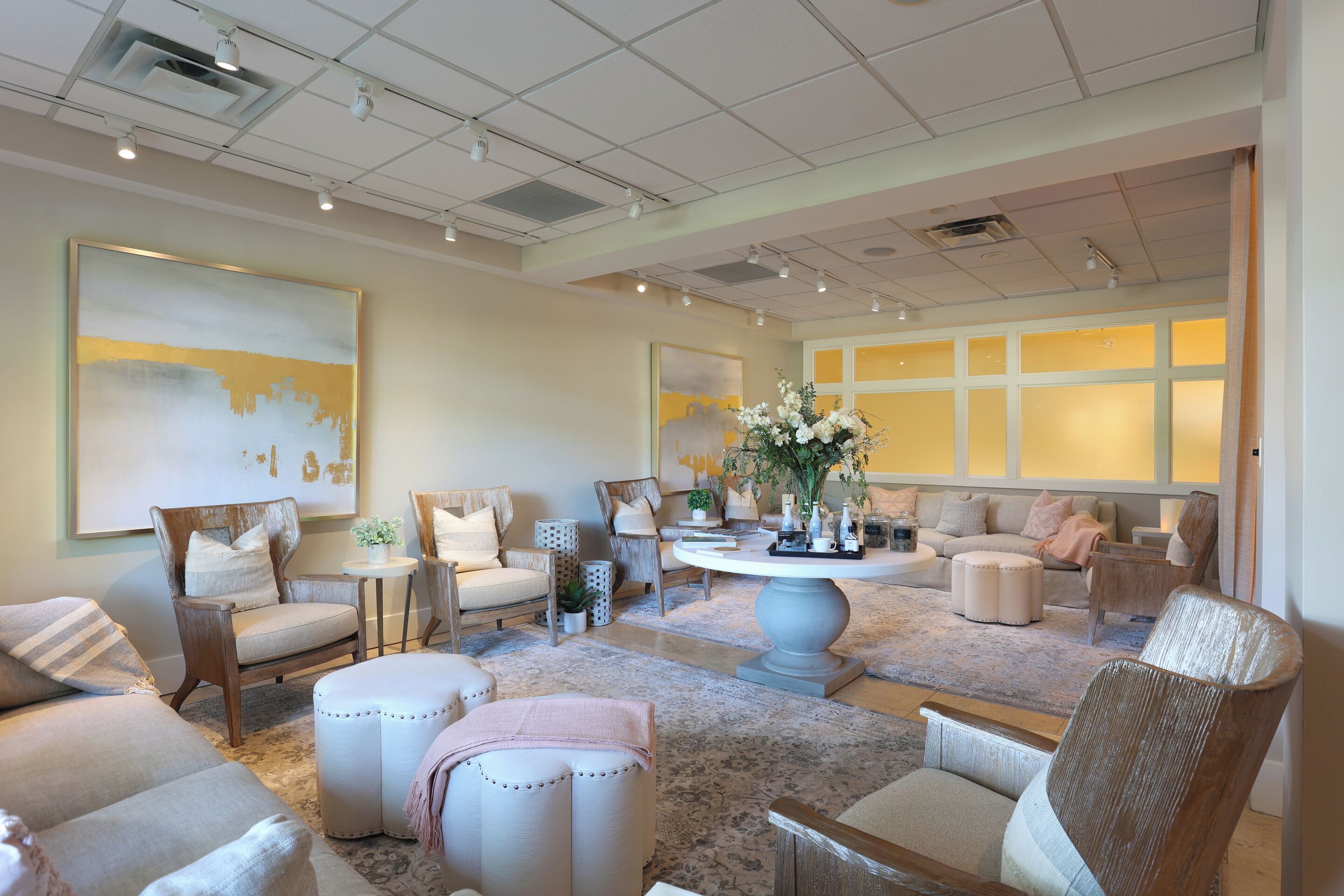 A spacious living room with a large window, a round coffee table, and multiple seating options including a sofa and chairs.
