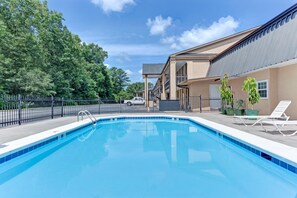 A swimming pool with a clear blue water, surrounded by a fence, and a building with a balcony in the background. - Super Inn & Suites Carrollton,West Georgia (Carrollton)