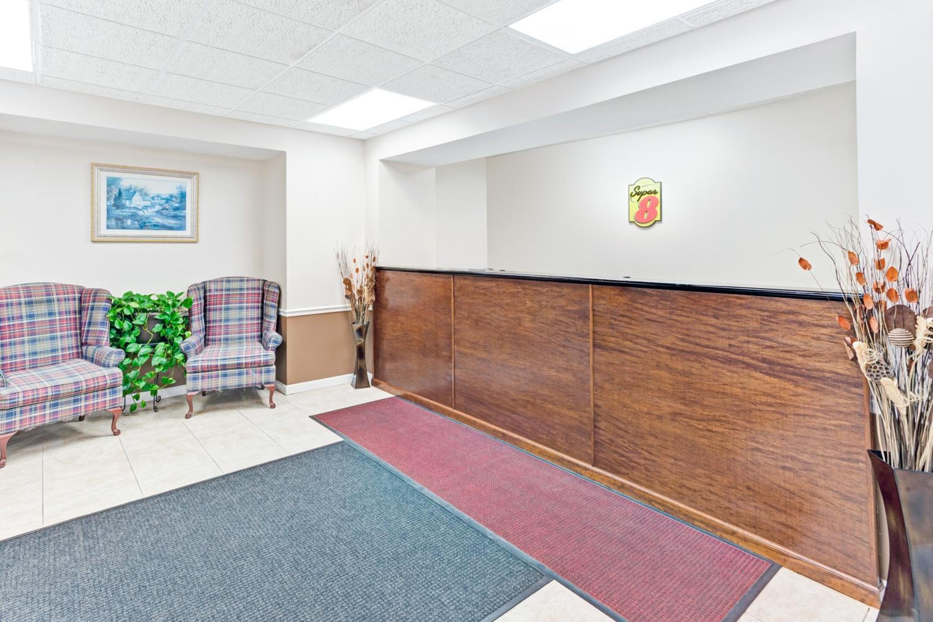 A reception area with a wooden reception desk, two plaid armchairs, a green plant, and a framed picture on the wall.
