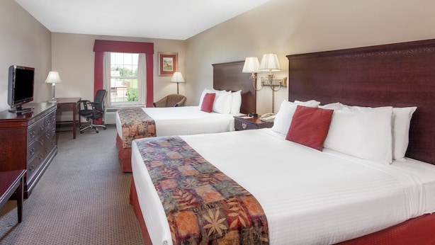 A hotel room with two beds, a desk, a TV, and a window with a view. - Super Inn & Suites Carrollton,West Georgia (Carrollton)