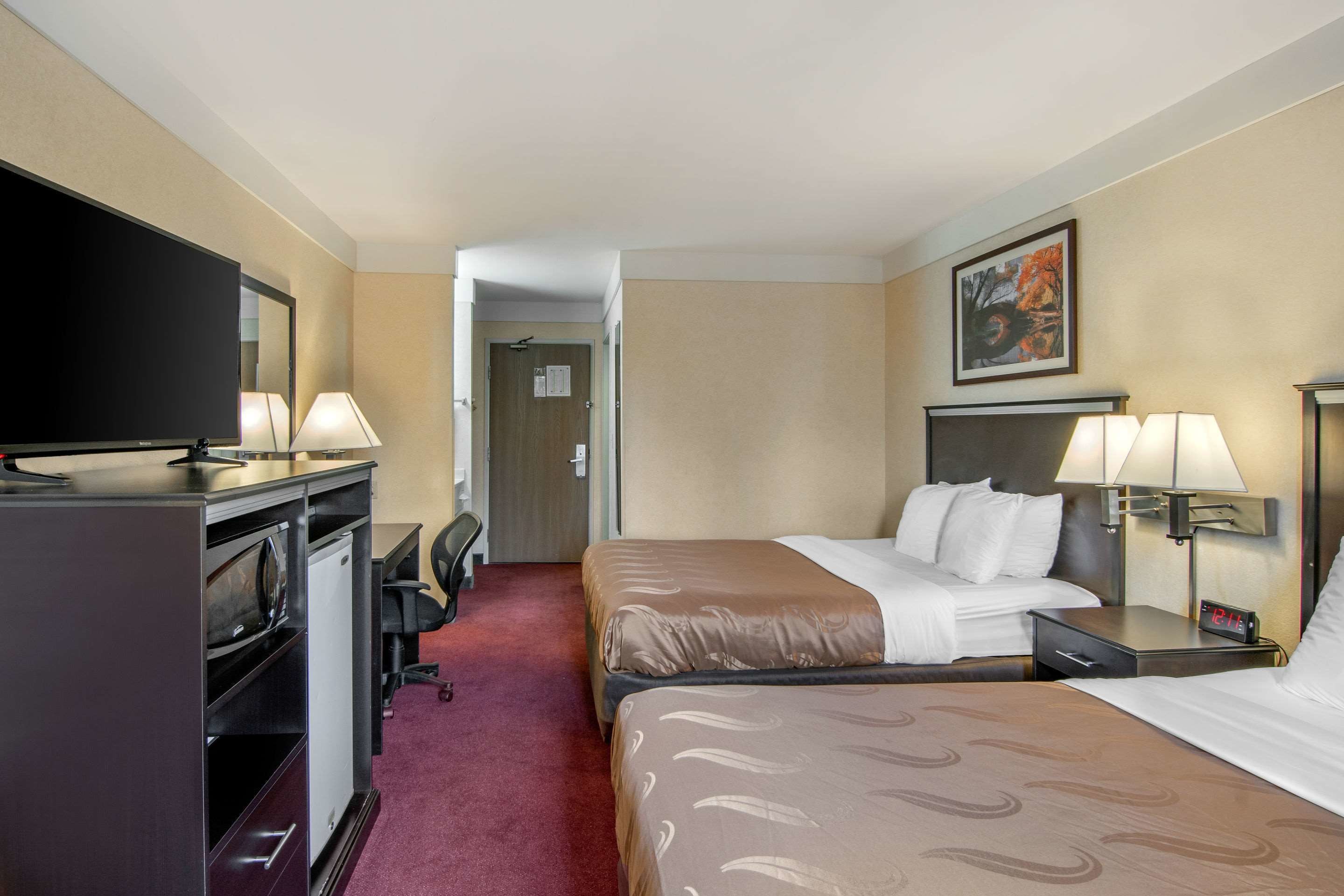 Ein Hotelzimmer mit Bett, Schreibtisch mit Computer, Fernseher und Lampe.