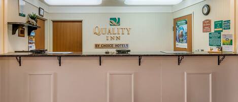 A reception desk with a sign reading "Quality Inn by Choice Hotels".