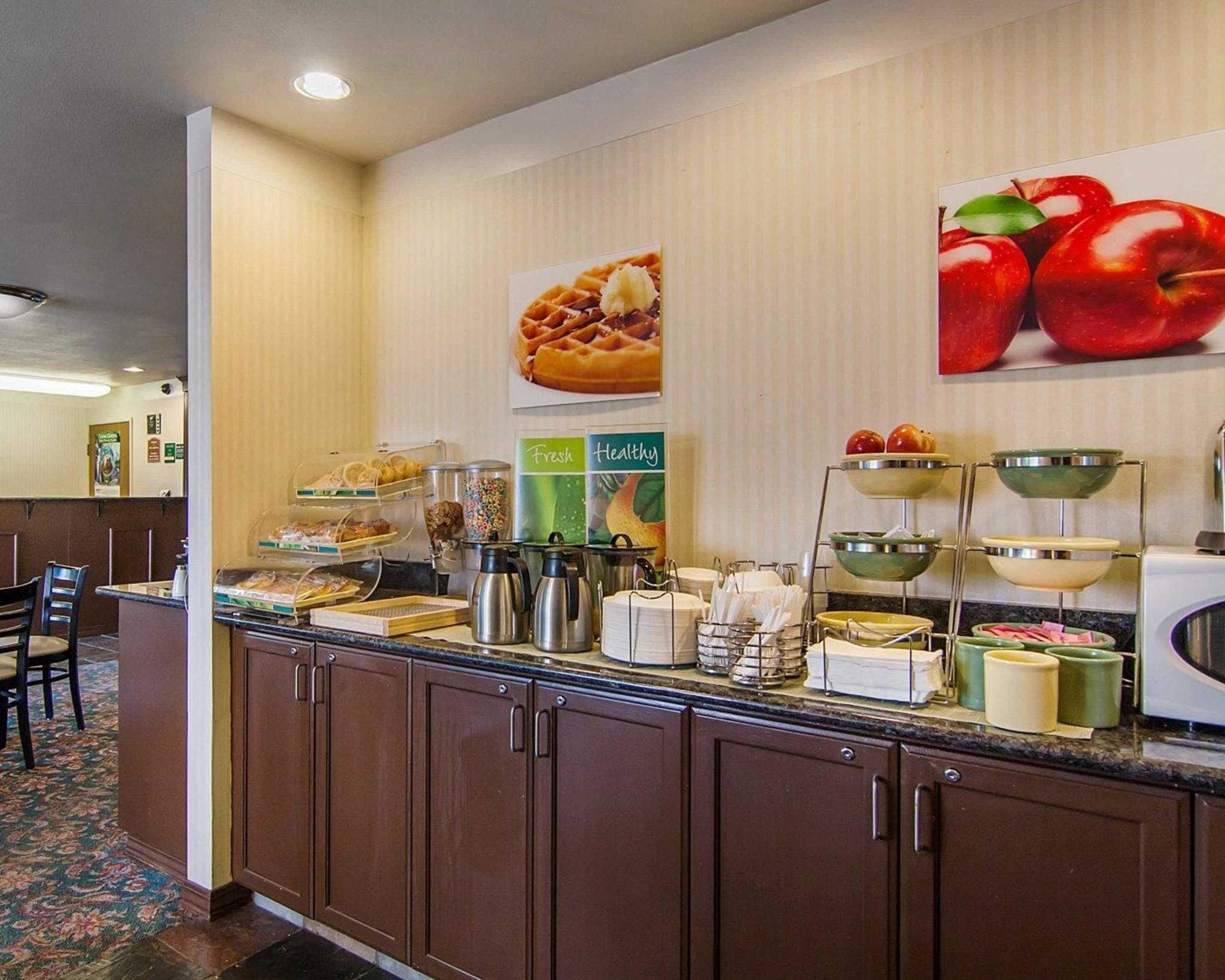 Ein Bereich zum Frühstücksbuffet mit einer Theke, auf der verschiedene Speisen, ein Hinweis auf Waffeln und frisches Obst präsentiert werden.