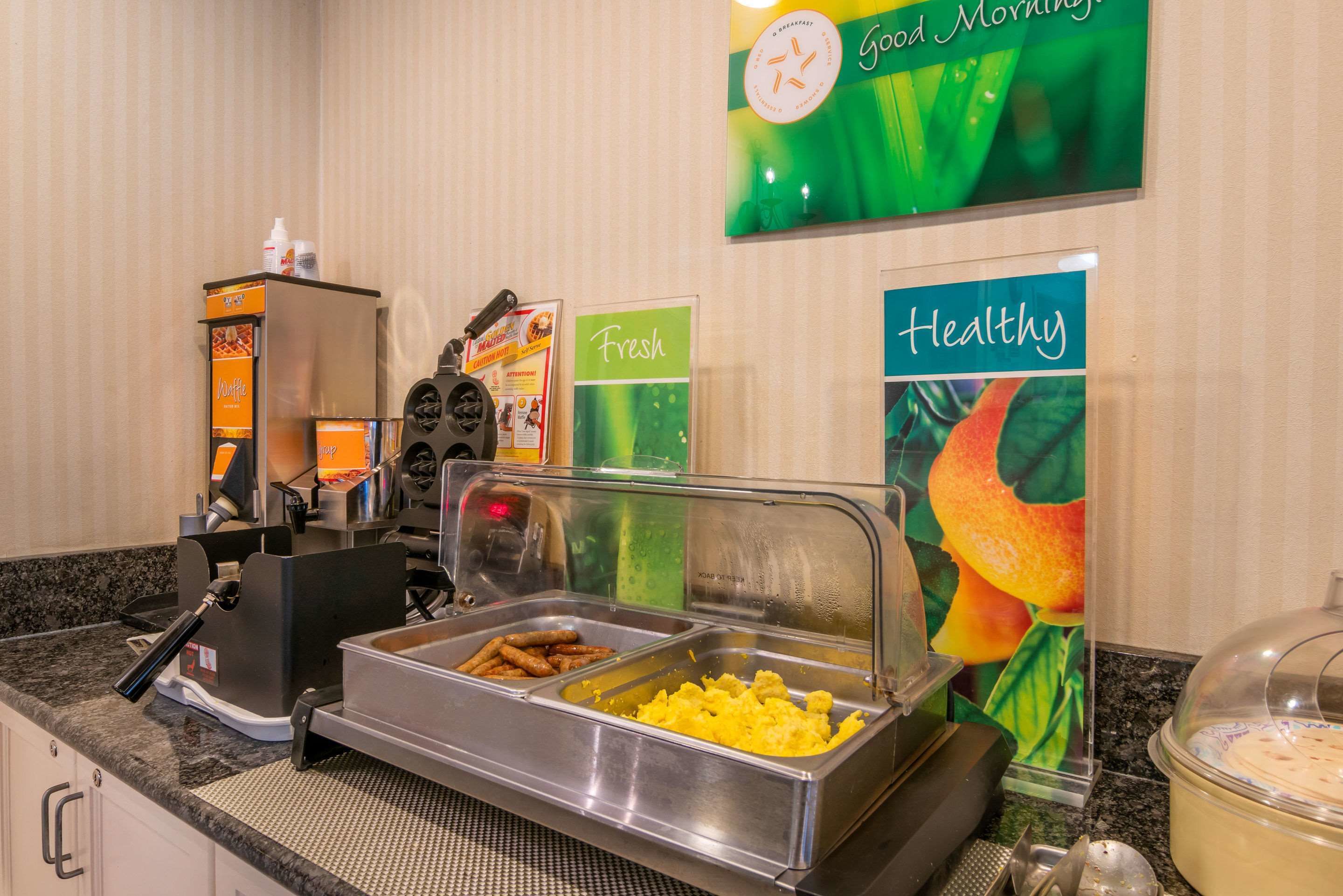 A buffet setup with various food items, a coffee machine, and a clock on the wall.