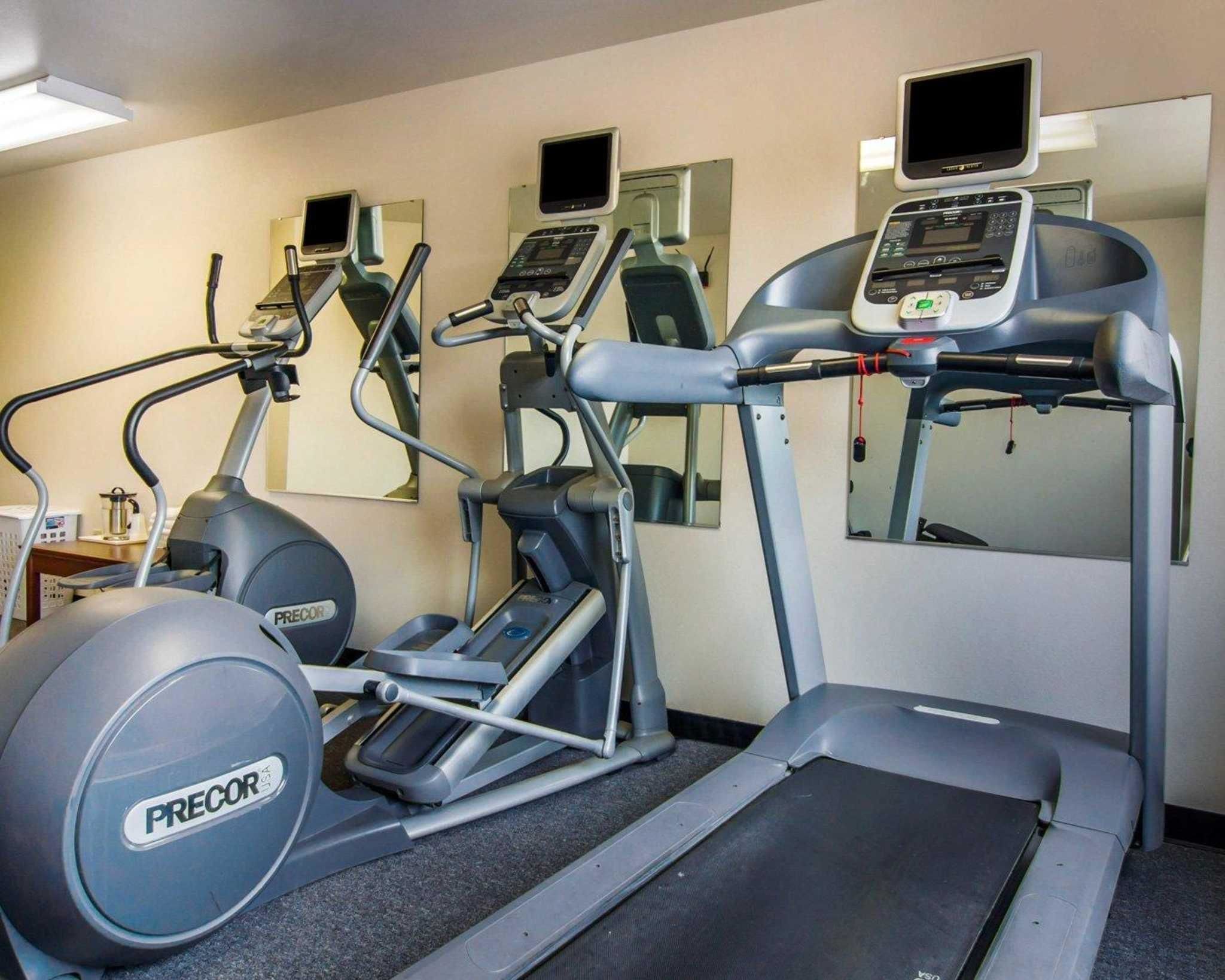 Un gimnasio con cintas de correr, elípticas y pelotas de ejercicio.