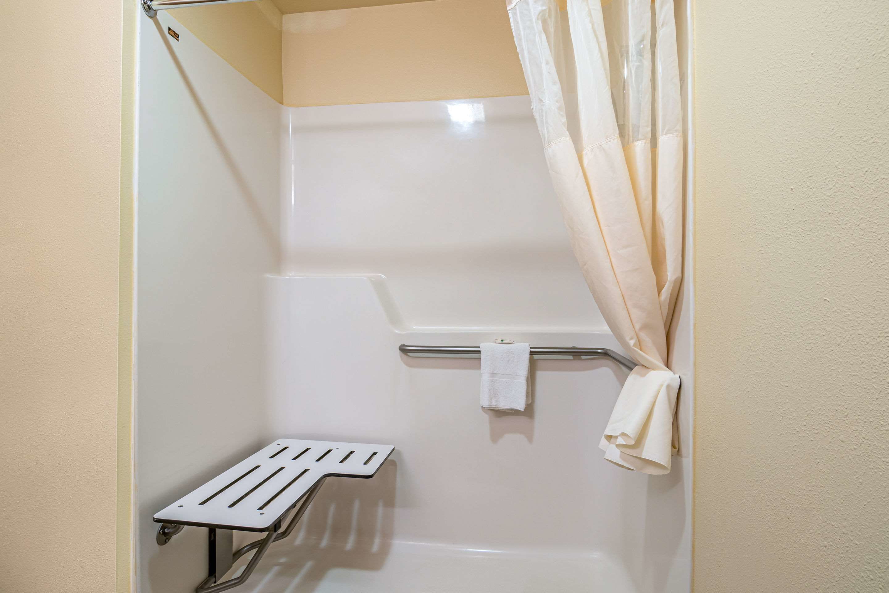 A shower with a grab bar, a towel rack, and a shower curtain.