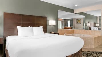 Quarto de hotel com uma cama grande, banheiro com banheira e um espelho refletindo o quarto.