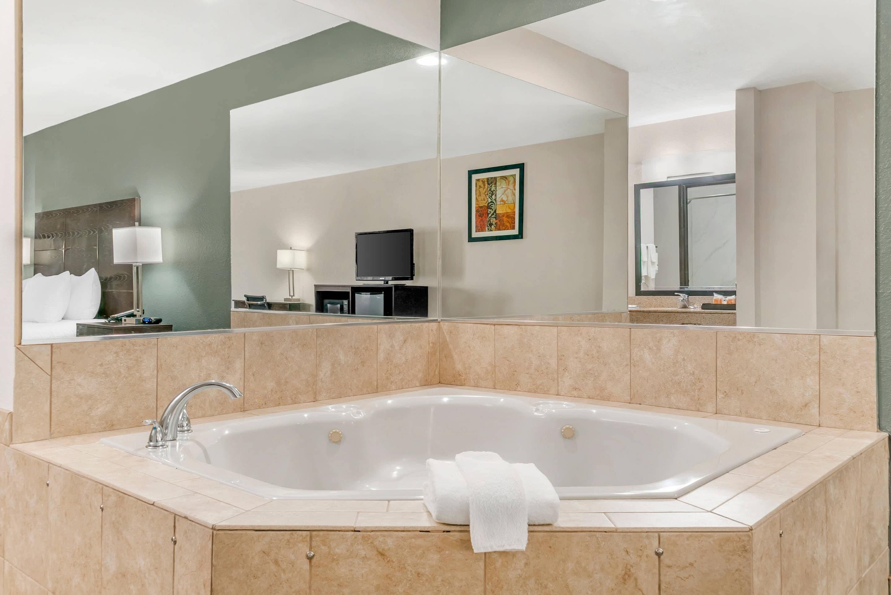 Un baño moderno con una bañera independiente grande, un tocador con espejo y un televisor de pantalla plana montado en la pared.