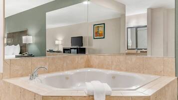 Un baño moderno con una bañera independiente grande, un tocador con espejo y un televisor de pantalla plana montado en la pared.