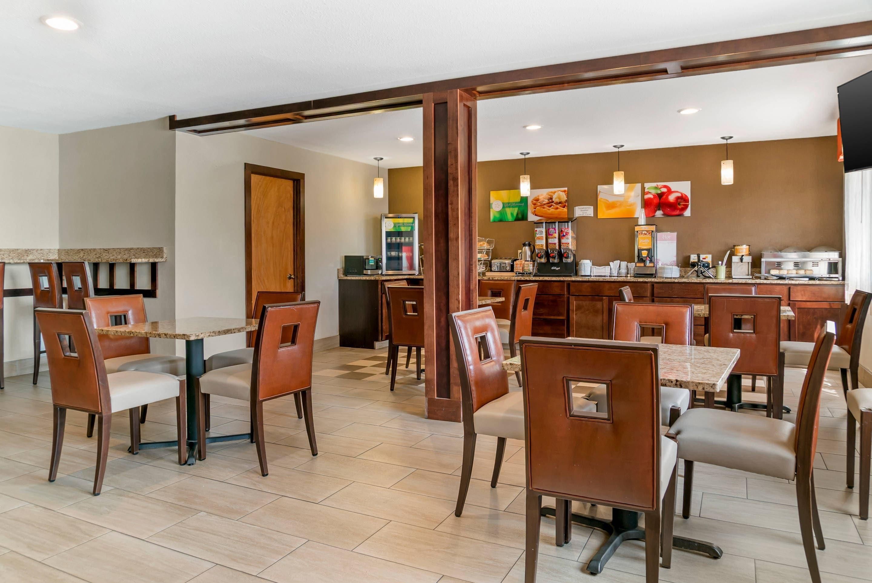 Un comedor de hotel con varias mesas y sillas, una estación de café y una pared decorada con imágenes de frutas.