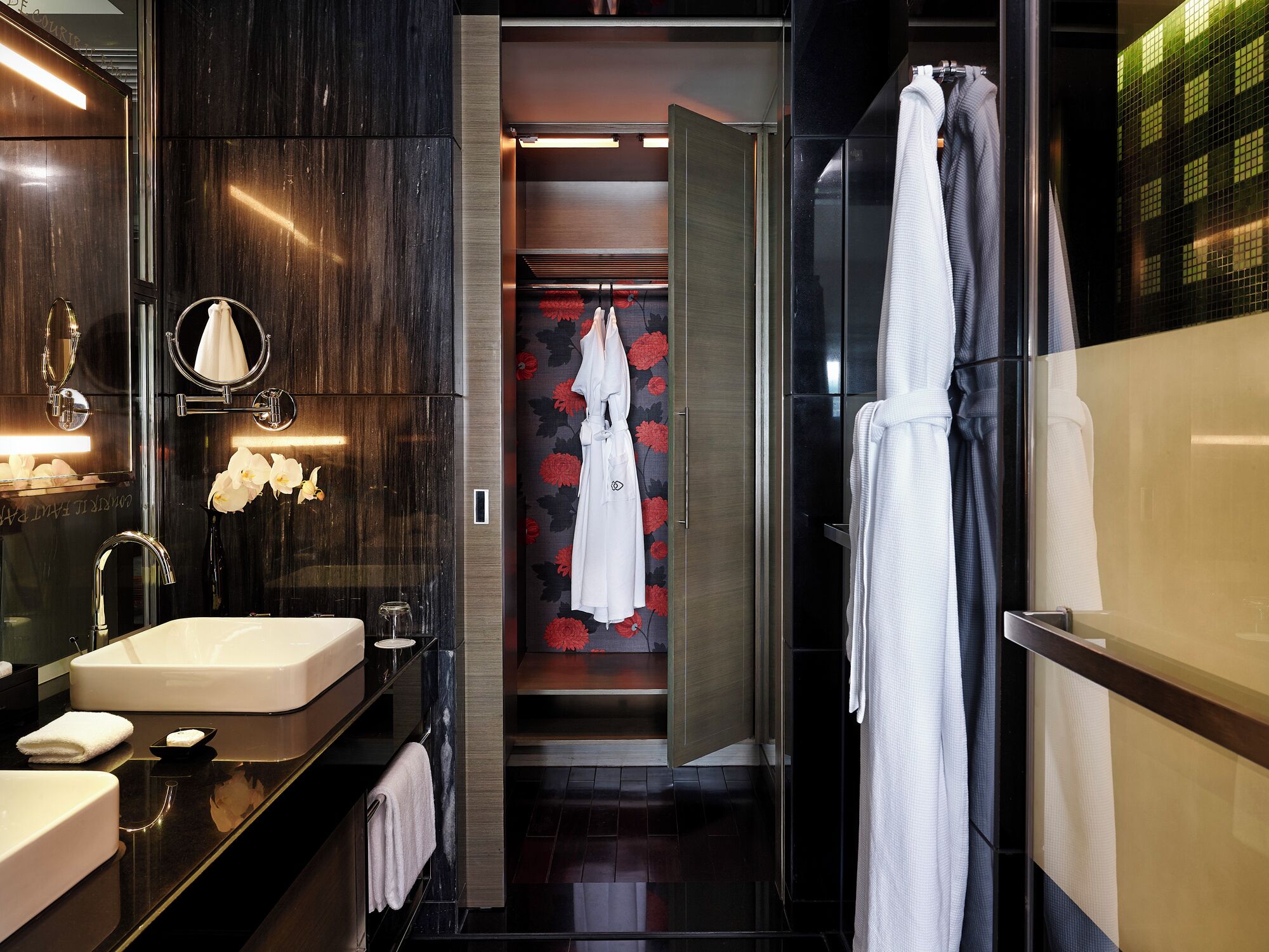Un baño moderno con un espejo grande, dos lavamanos, un perchero para bata y una zona de ducha.