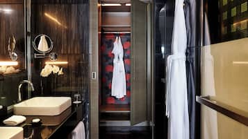 Un baño moderno con un espejo grande, dos lavamanos, un perchero para bata y una zona de ducha.
