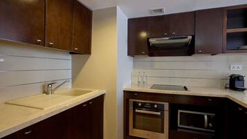 A modern kitchen with dark wood cabinets, a stainless steel sink, and built-in appliances including an oven and microwave.