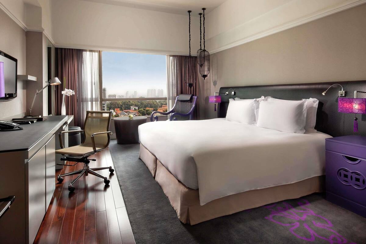 Une chambre d’hôtel avec un lit, un bureau, une chaise et une vue sur la ville.