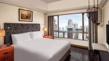 Habitación de hotel con una cama grande, vistas a la ciudad, una obra de arte enmarcada y una lámpara de araña moderna.