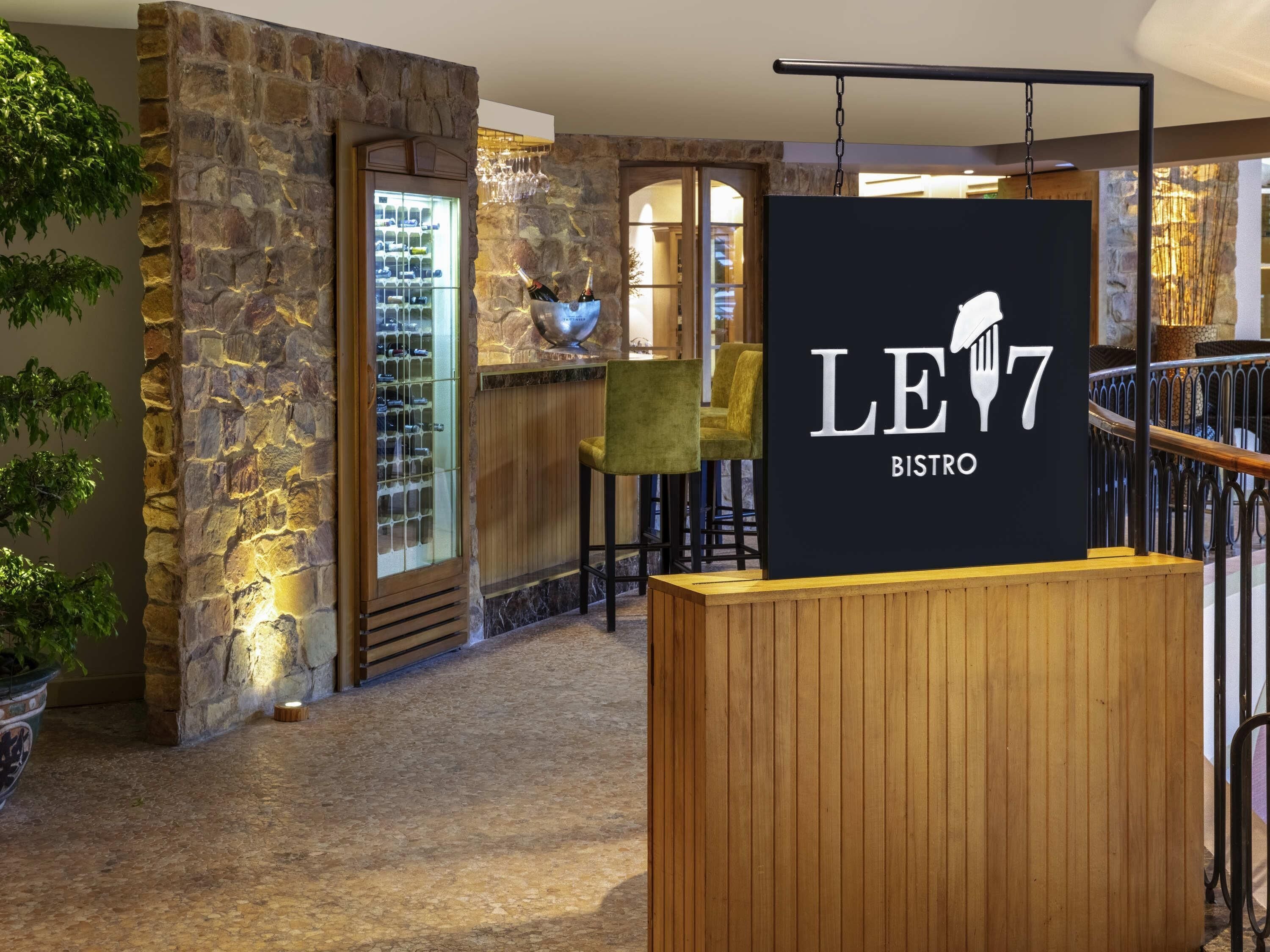 Un bistrot avec un mur en pierre, un réfrigérateur à vin et une enseigne indiquant le nom de l’établissement.