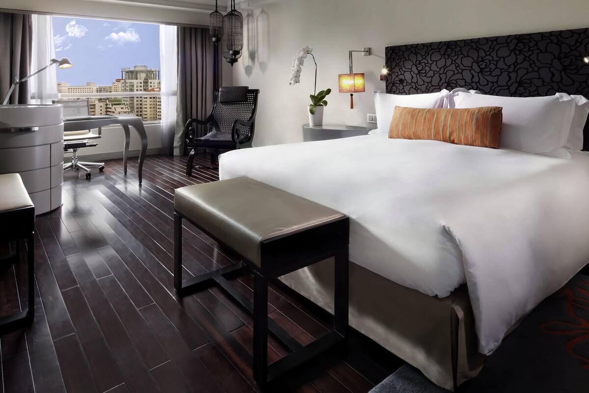 Une chambre d’hôtel avec un grand lit, un bureau, une chaise et une vue sur la ville.