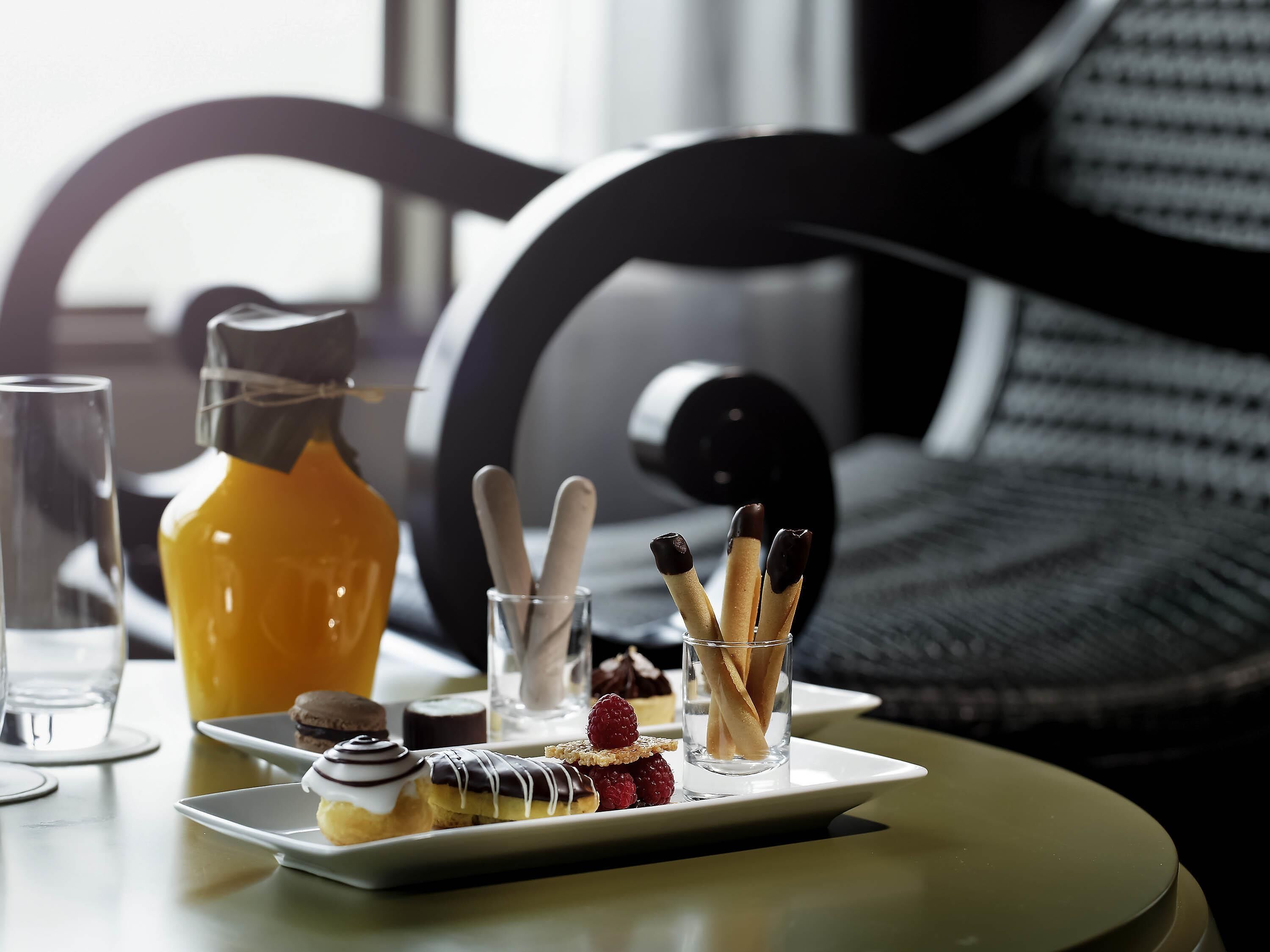 Een ontbijfwagen met gebak, een glas jus d'orange en een koffiepot op een tafel.