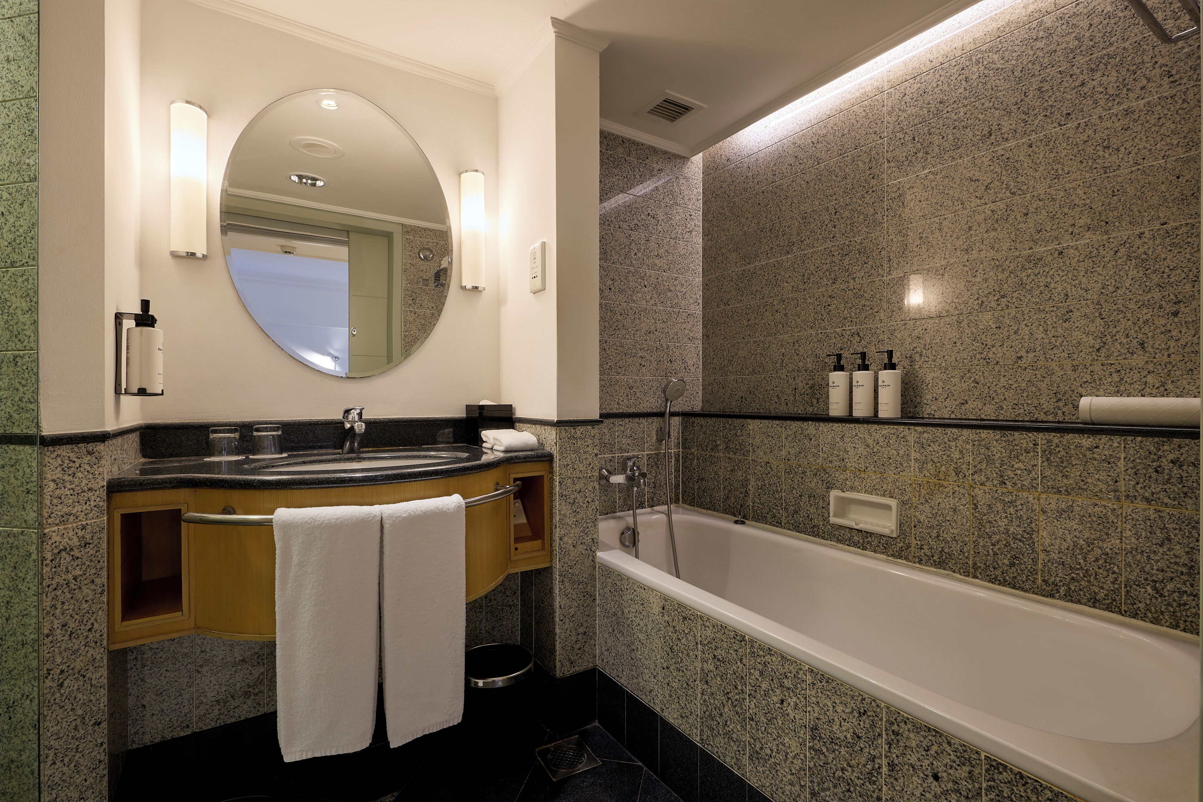 A modern bathroom with a granite countertop sink, a large mirror, and a standalone bathtub.