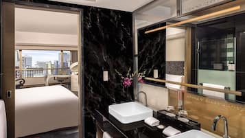 Una habitación de hotel moderna con una cama grande, dos lavamanos, un espejo y vistas a la ciudad.