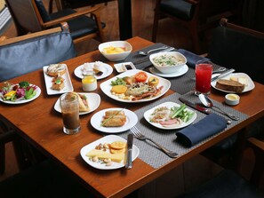 Une table à manger avec différents plats, couverts et une boisson.
