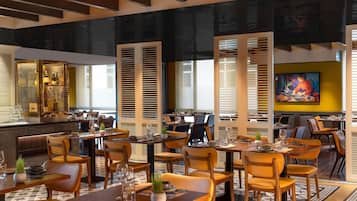 A restaurant with multiple dining tables, chairs, and a bar area.