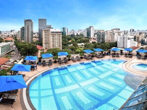 Une piscine sur le toit, agrémentée de chaises longues et de parasols, entourée d’immeubles de la ville.