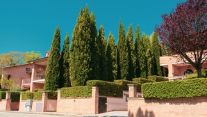 A residential building with a brick facade, multiple balconies, and a well-maintained hedge. - Carpediem Assisi Living Club (Assisi)