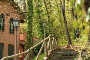 A stone staircase with a wooden handrail leading up to a brick building with green shutters and a lantern post. - Carpediem Assisi Living Club (Assisi)