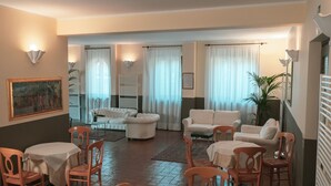 A spacious living room with a dining area, featuring a fireplace, white sofas, and a large painting on the wall. - Carpediem Assisi Living Club (Assisi)