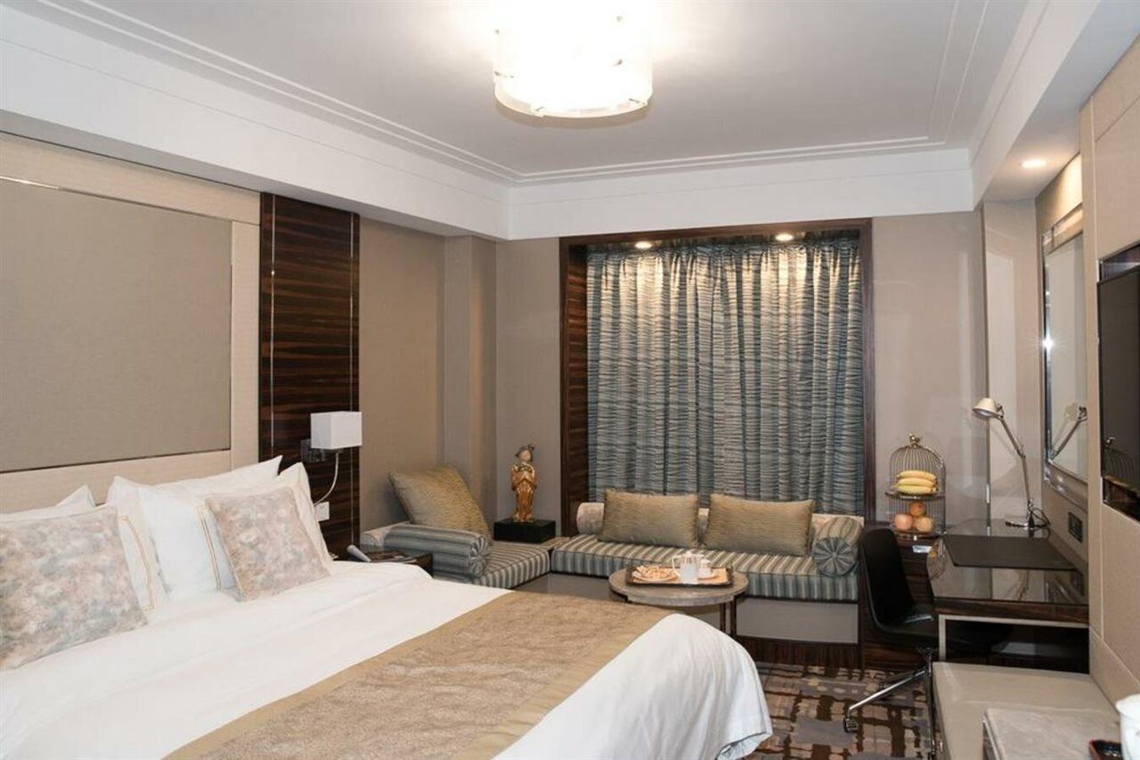 A hotel room with a large bed, a sofa, a desk, and a television.