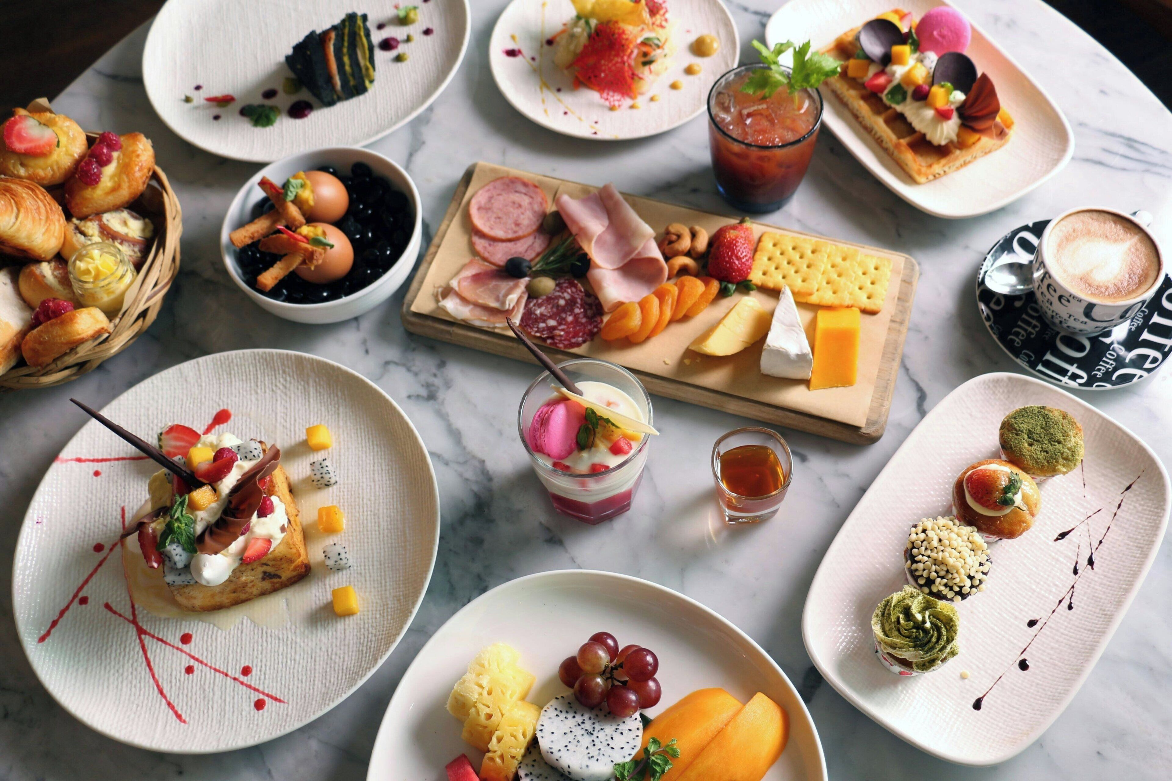 Diverse gerechten en desserts op een marmeren tafel.