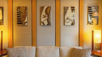 A modern living room with a beige sofa, abstract wall art, and a glass coffee table with a vase.
