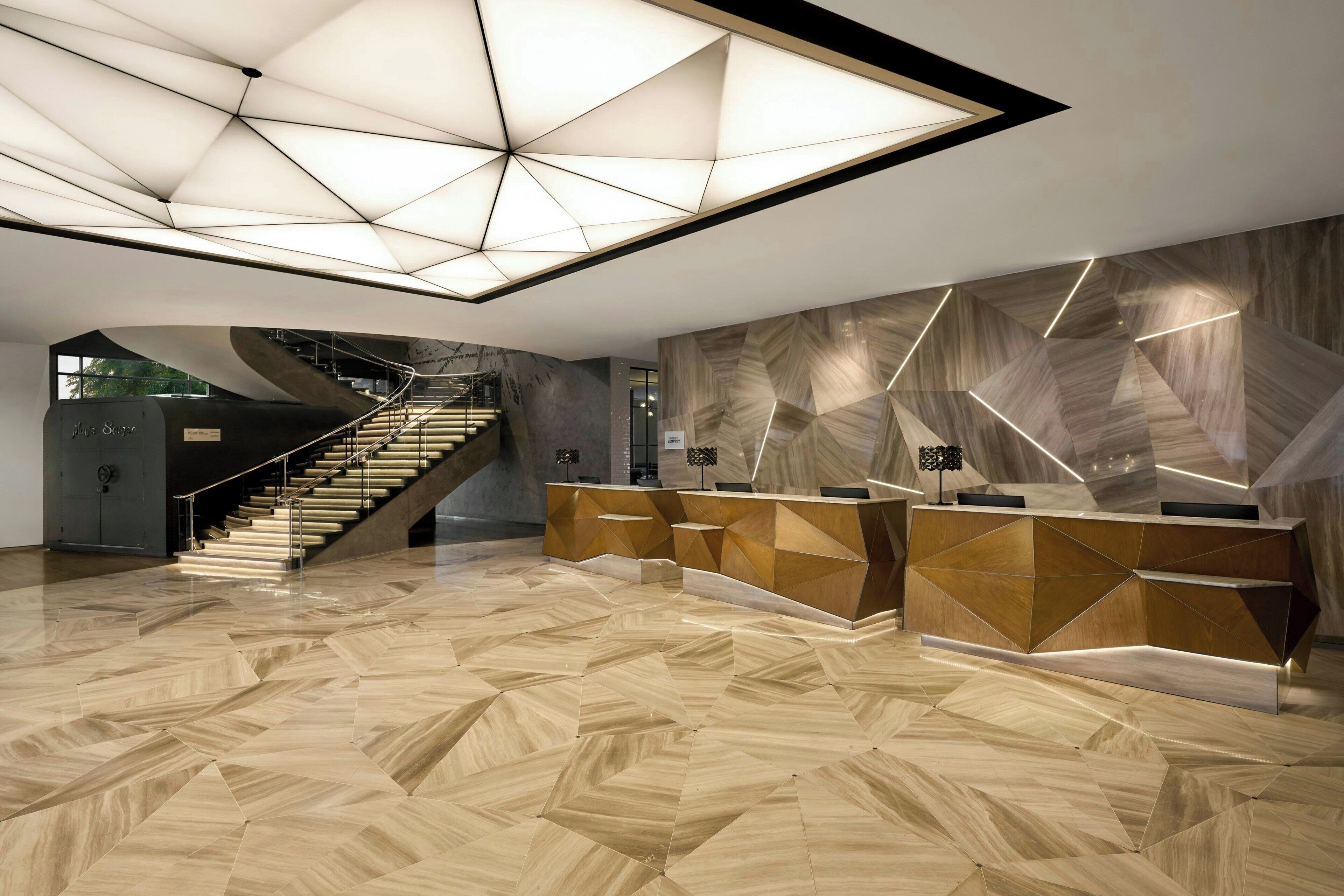 En moderne reception med et geometrisk gulvmønster, en central trappe og et unikt loftsdesign.