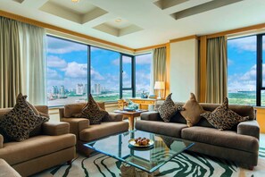 A modern living room with a glass coffee table, two sofas with patterned cushions, a view of a cityscape through large windows, and a zebra-patterned rug. - Renaissance Riverside Hotel Saigon (Ho Chi Minh City)
