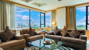 A spacious living area with a large window offering a city view, two sofas with patterned cushions, a glass coffee table, and a small side table with a lamp. - Renaissance Riverside Hotel Saigon (Ho Chi Minh City)