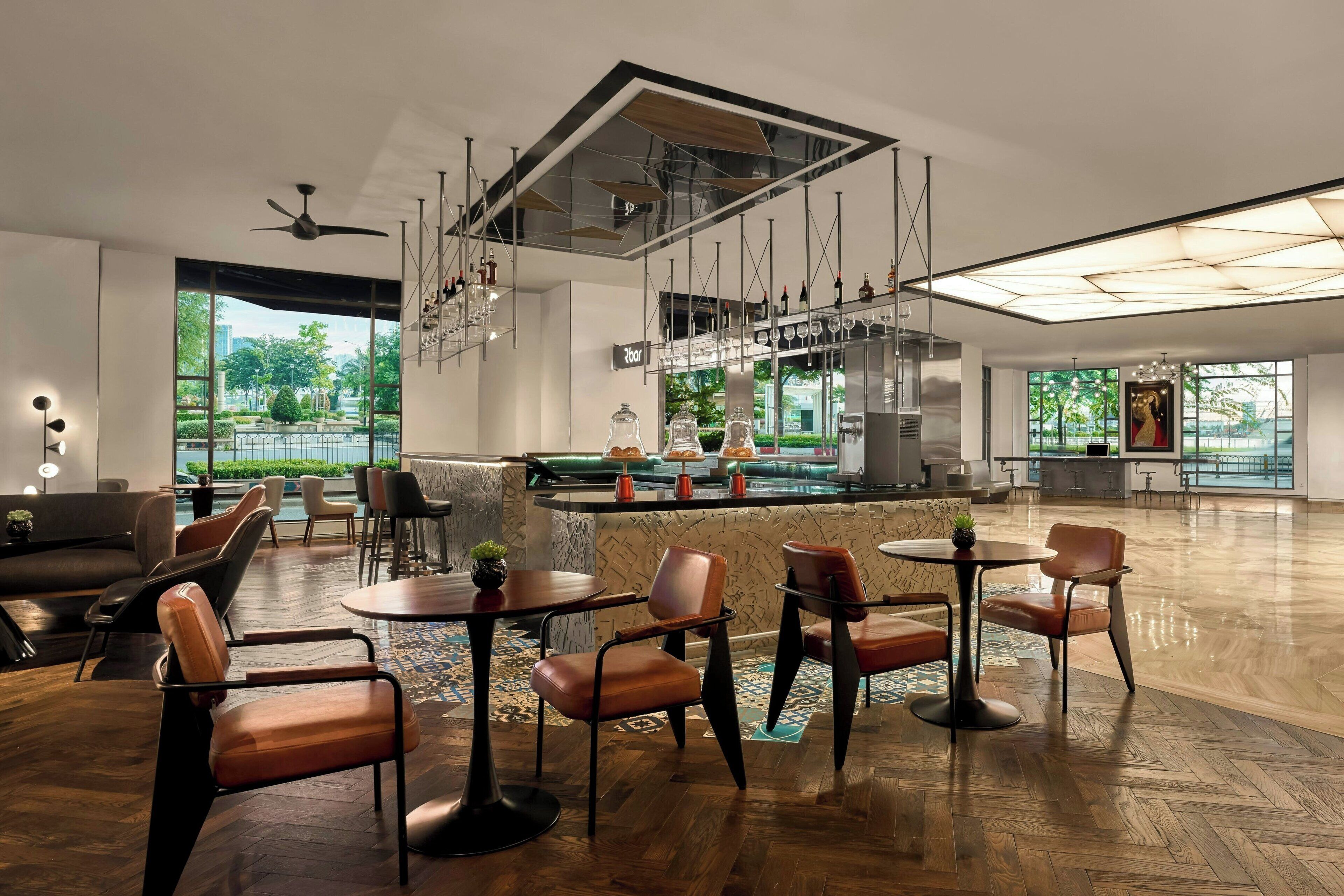 A spacious, modern lounge area with a bar, seating arrangements, and large windows offering views of the outdoors.